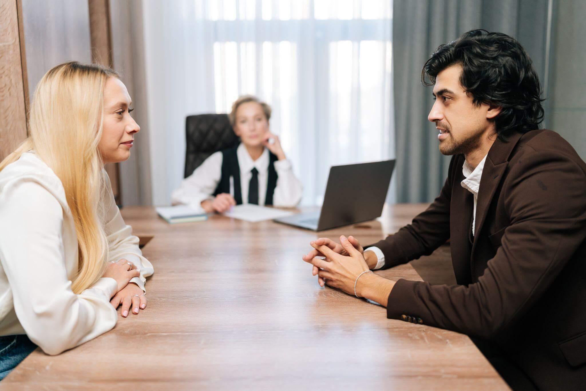 two people sitting face to face having a discussion with a moderator in the background